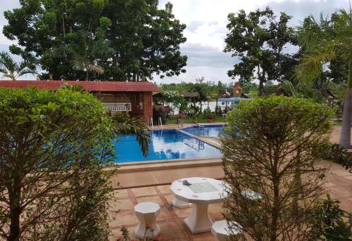 Ban Nong PhaiChangthai Comfort Guest House的前方设有带桌子和树木的游泳池