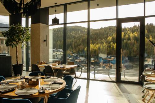 布克维Rest&Ski Spa Resort的餐厅设有桌椅和大窗户。