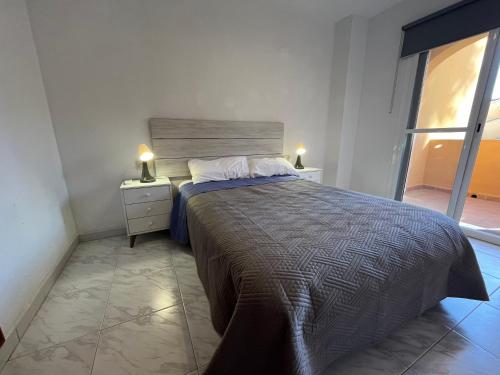 苏埃卡Casa adosada junto a la playa de El Perelló的一间卧室配有带2个床头柜和1扇窗户的床