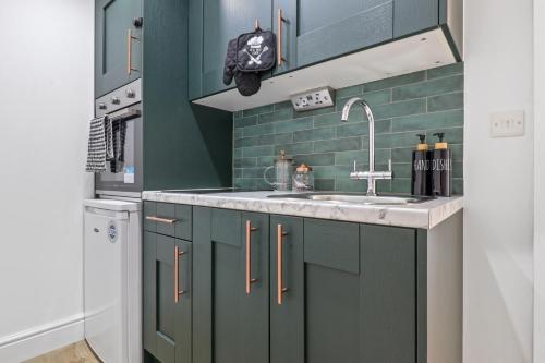 伦敦Finsbury Park Studios的厨房配有绿色橱柜和水槽