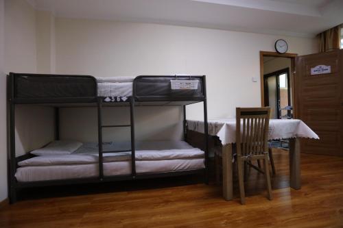 乌兰巴托Alpha Guest House的配有2张双层床的客房配有桌子和椅子