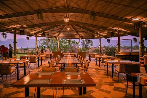 马尔舍吉加特Saj By The Lake, Malshej Ghat的一间设有木桌和椅子的餐厅,享有美景。