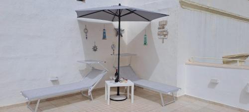 加利波利Cinque terrazze - Casa d'epoca con vista mare的一间设有两张长椅和一把遮阳伞的房间