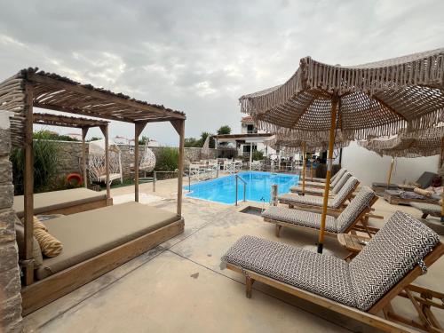 斯卡拉Koukounari Apartments的一个带椅子和遮阳伞的游泳池的度假酒店