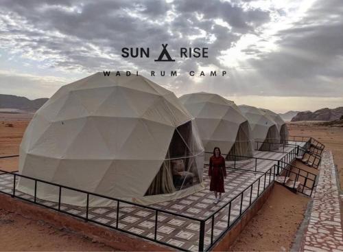 瓦迪拉姆Sunrise Wadi Rum Camp的站在沙漠中一排帐篷前面的女人