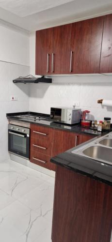 MuseleShalom Apartments Kalumbila的厨房配有木制橱柜和炉灶烤箱。