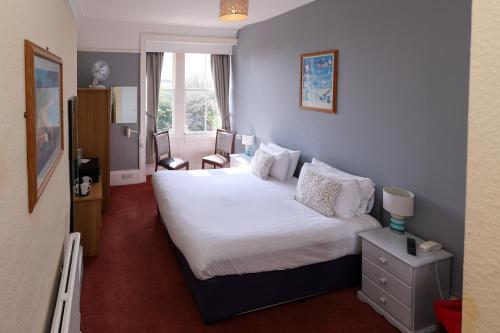 埃克斯茅斯庄园酒店的卧室配有白色的床和窗户。