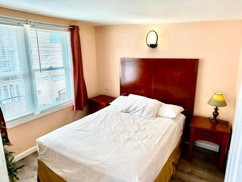 大洋城Atlantic Breeze Motel & Apartments的一间卧室配有一张红色床头板的床和两个窗户