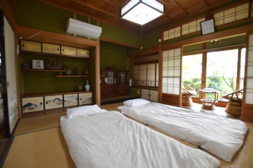 津市Guest House Ilonggo的配有两张床铺的绿色墙壁和窗户