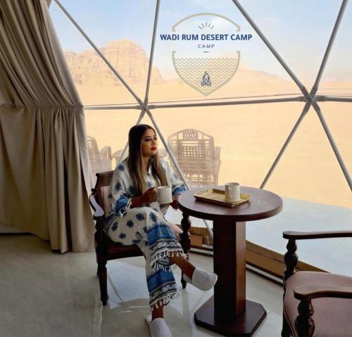 瓦迪拉姆Wadi Rum desert camp的坐在桌子旁喝杯咖啡的女人