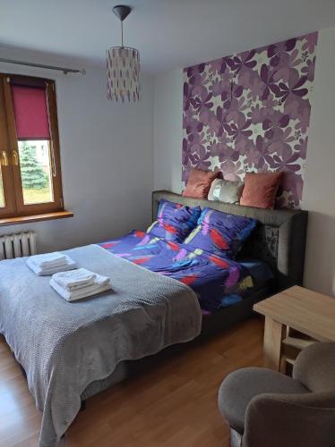 布斯克·兹德鲁伊Komfortowe mieszkanie的一间卧室配有一张床和紫色的墙壁