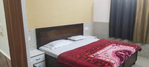 马图拉Goroomgo Kunj Residency Mathura Near Bus Stand - Parking Facility & Restrurant的一间卧室配有一张床铺,床上铺有红色毯子