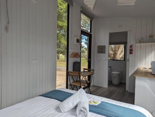 Dadswells BridgeTiny House 16A at Grampians Edge的一间卧室配有一张床,厨房配有桌子