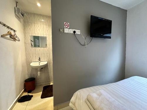 梳邦再也De UPTOWN Hotel @ Subang Jaya的一间带床和水槽的浴室以及一台电视。