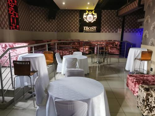 比勒陀利亚Ebony Lounge Hotel and Event Center的餐厅配有白色的桌椅和时钟