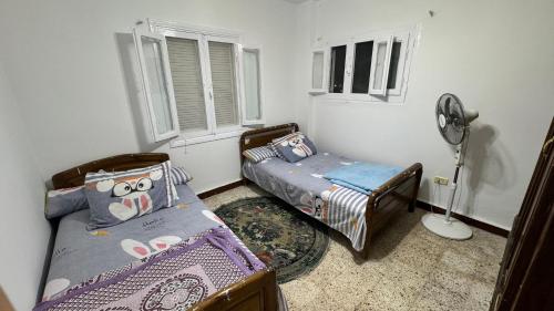 伊斯梅利亚شقق وشاليهات بمدينة النورس的一间卧室配有两张单人床和风扇