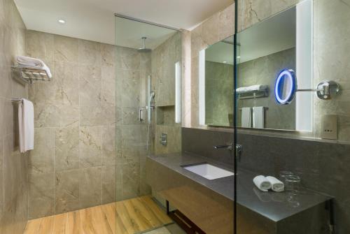 马斯喀特IntercityHotel Bawshar Muscat的浴室配有盥洗盆和带镜子的淋浴