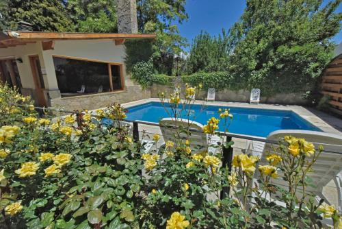 圣马丁德洛斯Hosteria Monteverde by Visionnaire的种有黄色花卉的花园和一个游泳池