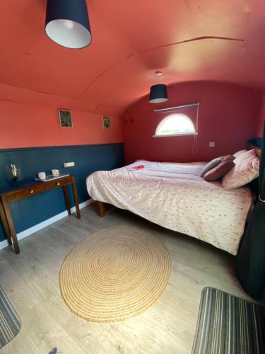 The Hares Hut at Carrigeen Glamping的一间卧室配有一张红色墙壁的床