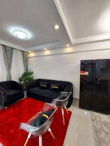 MutomoLuxury Apartment Lavington的客厅配有黑色沙发和红色地毯。