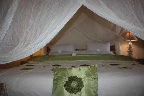 罗威那乔格罗海滩别墅的一间卧室配有一张带绿色枕头的天蓬床
