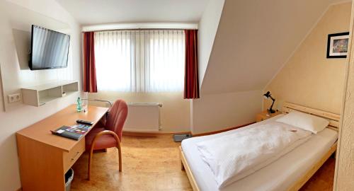 圣戈阿尔Hotel zur Loreley - Garni的小房间设有床、书桌和电视