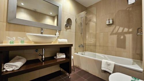 巴达霍斯博维达斯酒店的一间带水槽、浴缸和镜子的浴室