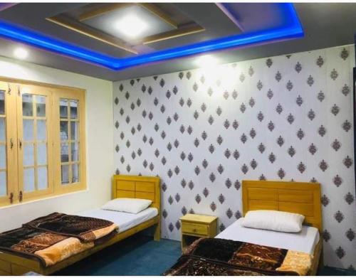 锡卡都Skardu city Guest house的蓝色天花板的客房内的两张床
