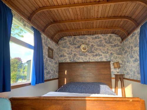 WatervlietIn de Wolf的一间卧室设有一张蓝色墙壁和木制天花板的床。