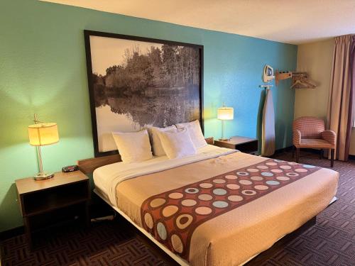 芒特弗农Super 8 by Wyndham Mount Vernon, IL的酒店客房设有一张床,墙上挂有绘画作品