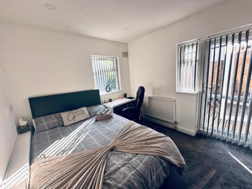 伯明翰Charming 2-Bed Apartment in Birmingham的卧室配有一张床、一张书桌和窗户。