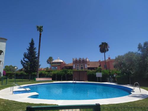 米哈斯科斯塔Coqueto apartamento en CalaHonda的棕榈树庭院里的一个大型游泳池