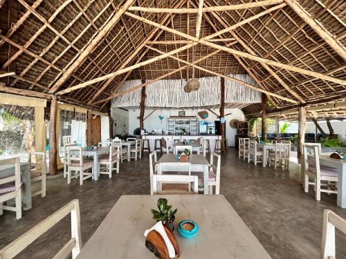 江比阿Bahari Beach Bungalows的拥有白色椅子和桌子的餐厅以及天花板。