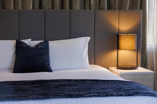 墨尔本墨尔本大臣酒店的一间卧室配有一张床和一张桌子上的台灯