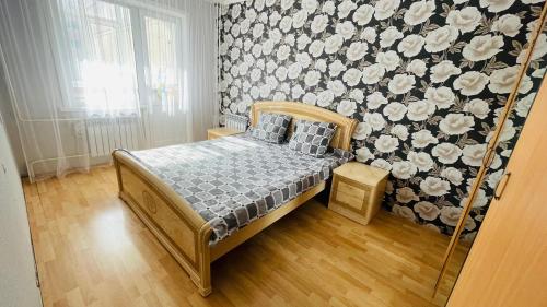科克舍套Трехкомнатная квартира на Центральном的一间卧室配有一张带花卉壁纸的床