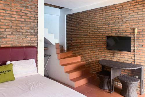 BanjarnegeriUrbanview Hotel Villa Q Gisting的卧室设有砖墙、一张床和电视