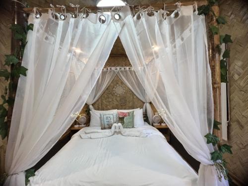 科隆Hidden Haven Coron的卧室配有带白色窗帘的天蓬床