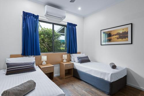 布鲁姆Cable Beach Apartments的配有蓝色窗帘的客房内的两张床