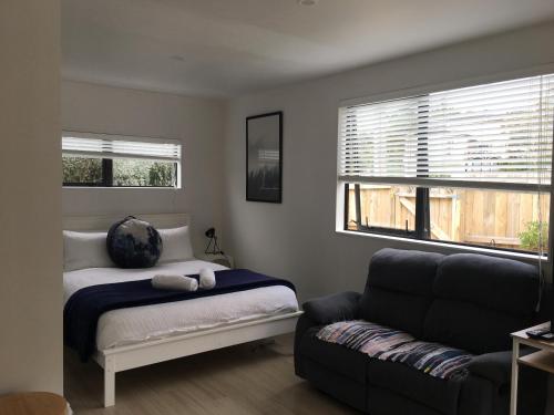 奥克兰West Auckland Delight Stay的一间卧室配有一张床、一张沙发和一个窗口