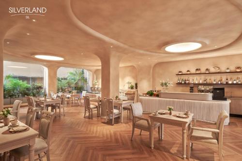 胡志明市Silverland Sil Hotel的一间带桌椅的餐厅和一间酒吧