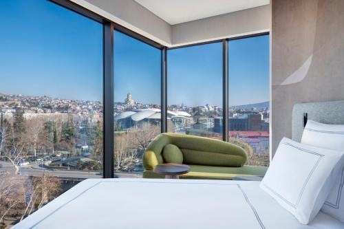第比利斯Swissôtel Tbilisi的一间卧室设有绿色椅子和大窗户