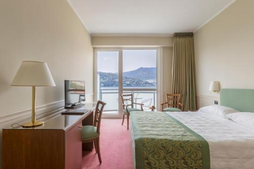 科莫巴格尔达高级酒店的配有一张床、一张书桌和一扇窗户的酒店客房