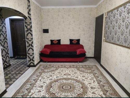 阿克托比Уютная двухкомнатная квартира в Актобе的地毯房间里一张红色的沙发