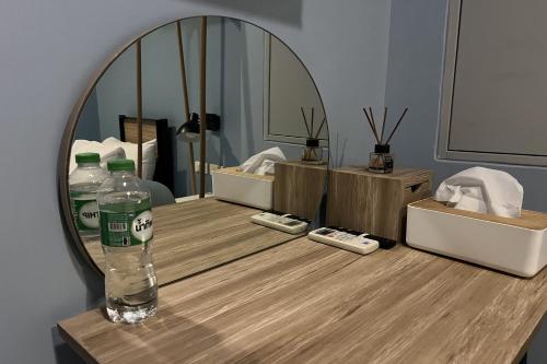 曼谷Simply Sleep Hostel的镜子前的柜台上的一瓶水