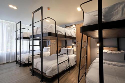 曼谷Simply Sleep Hostel的客房设有三张双层床,配有白色床单