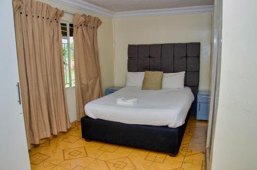 哈拉雷Riverstone Guest Lodge的一间卧室配有一张大床和大床头板