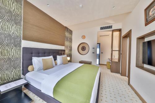 贝尔格莱德阿特拉商务套房酒店的一间卧室配有一张大床和一台平面电视