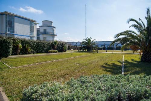 蒂勒尼亚Solidago Residence的一座公园,里面建有一座建筑,棕榈树和一座建筑