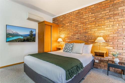 沃纳姆堡BIG4 Tasman Holiday Parks - Warrnambool的一间卧室设有一张床和砖墙