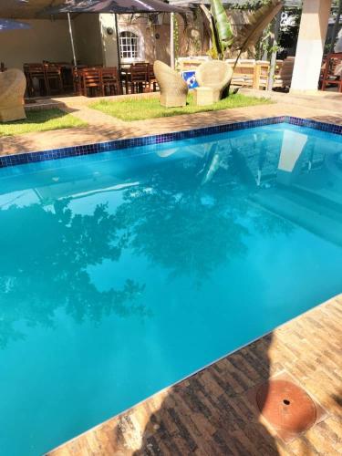 利隆圭Mpatsa Quest Hotels的蓝色游泳池配有椅子和遮阳伞